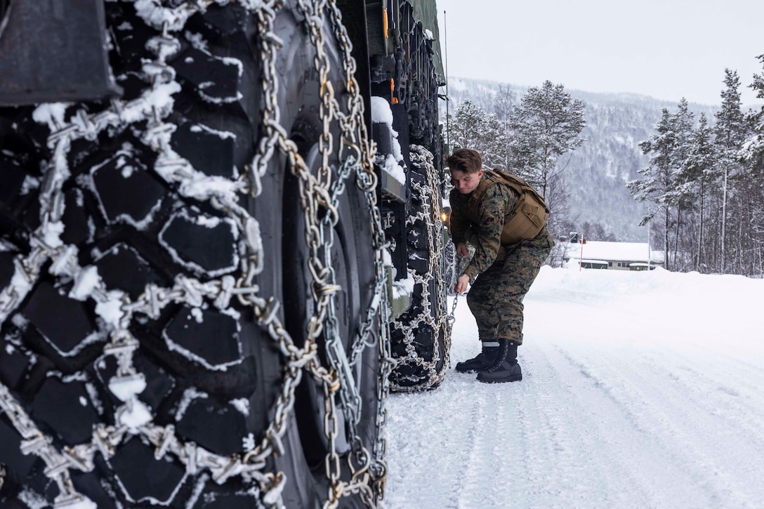 A Marine secures chains on a vehicle.