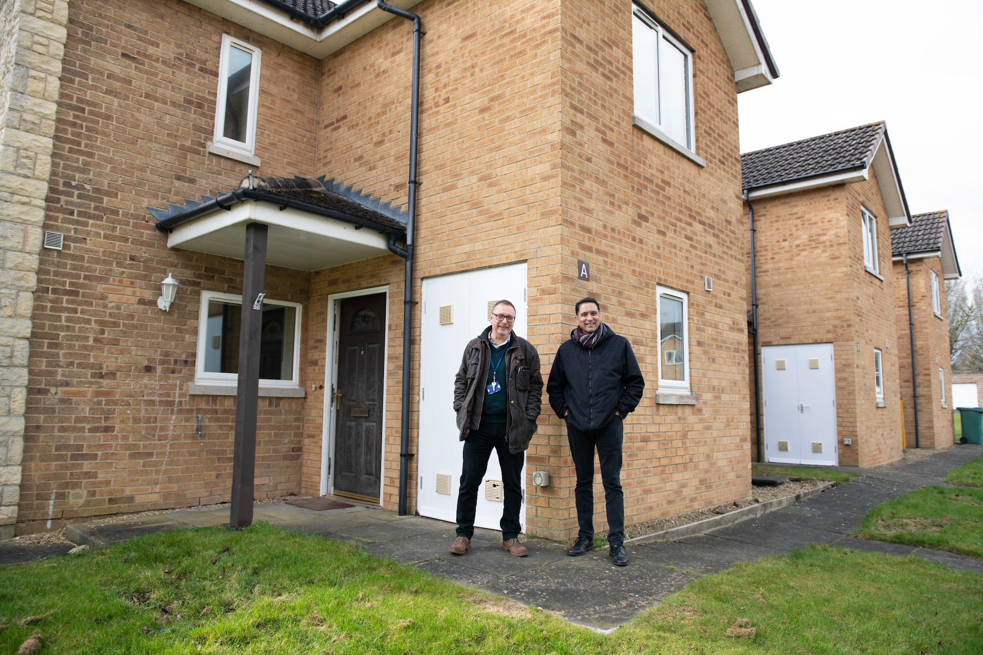 Ian Murray, left, 422d CES housing manager, and Hubert Braganza, right, 422d CES deputy housing manager, pose for a photo in front of a military family housing unit at RAF Fairford, England, March 6, 2023. Murray and Braganza have been assisting inbound personnel with inprocessing and moving to RAF Fairford. (U.S. Air Force photo by Staff Sgt. Jennifer Zima)