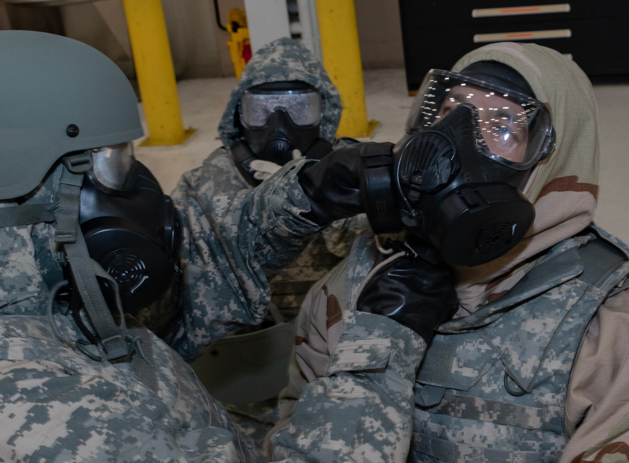 Airman checks another Airman's gas mask.