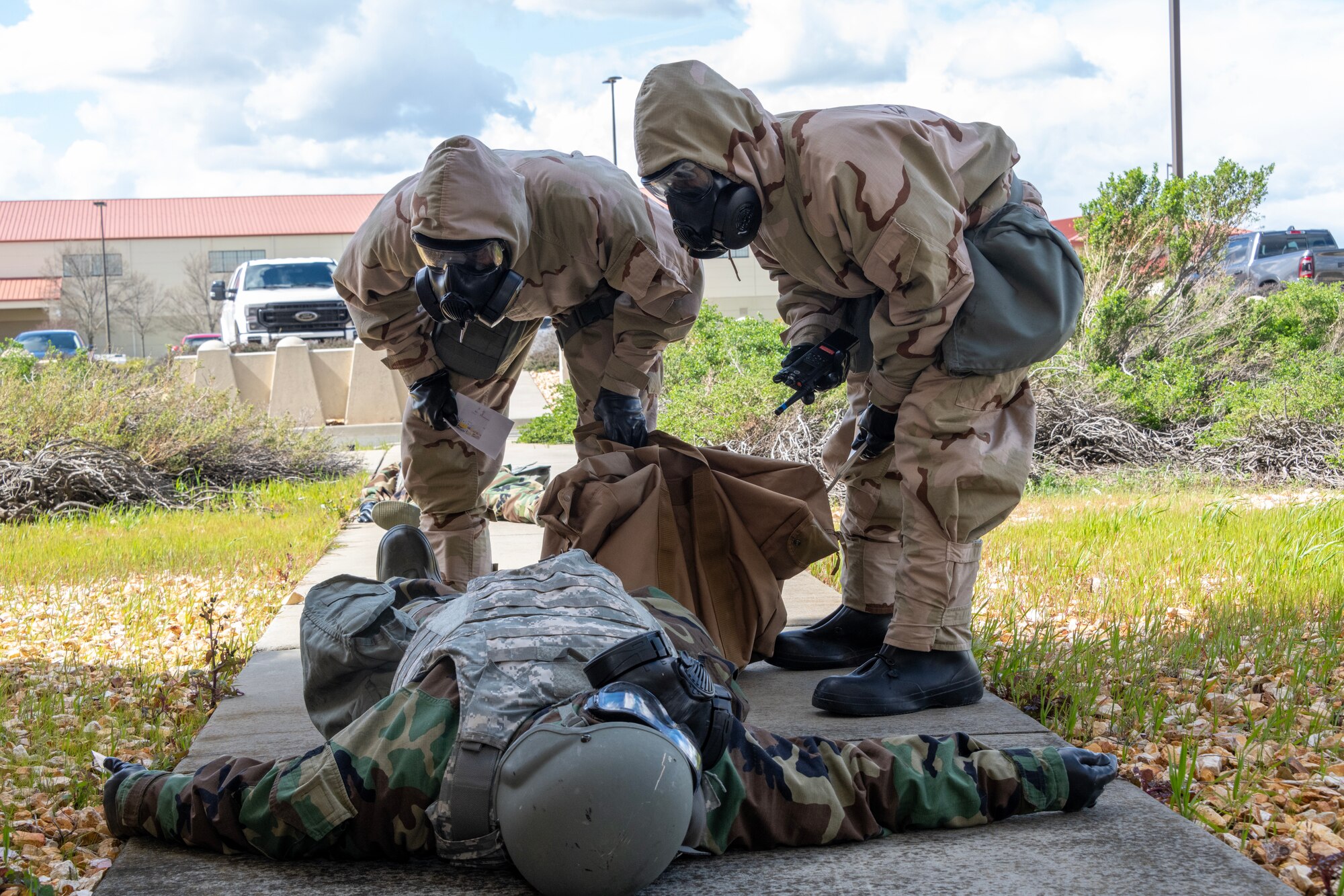 Two Airmen bend over another Airman lying on the ground