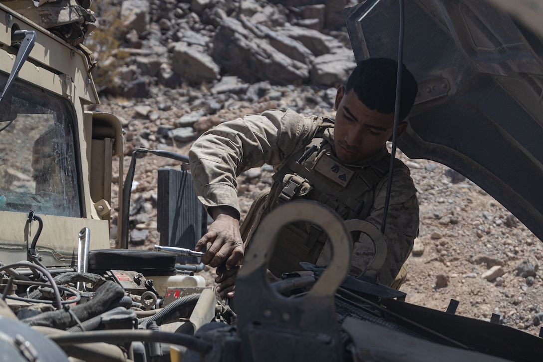 U.S. Marine Corps Cpl. Kevin M. Palaciosjovel, an automotive maintenance technician, with 3d Battalion, 5th Marine Regiment, 1st Marine Division, works on a Humvee during Marine Air Ground Task Force Warfighting Exercise (MWX) 3-22 at Marine Corps Air Ground Combat Center Twentynine Palms, California, May 2, 2022. MWX is a force-on-force exercise that challenges the Division to fight at scale against a free-thinking adversary. (Marine Corps photo by Cpl. Willow Marshall)