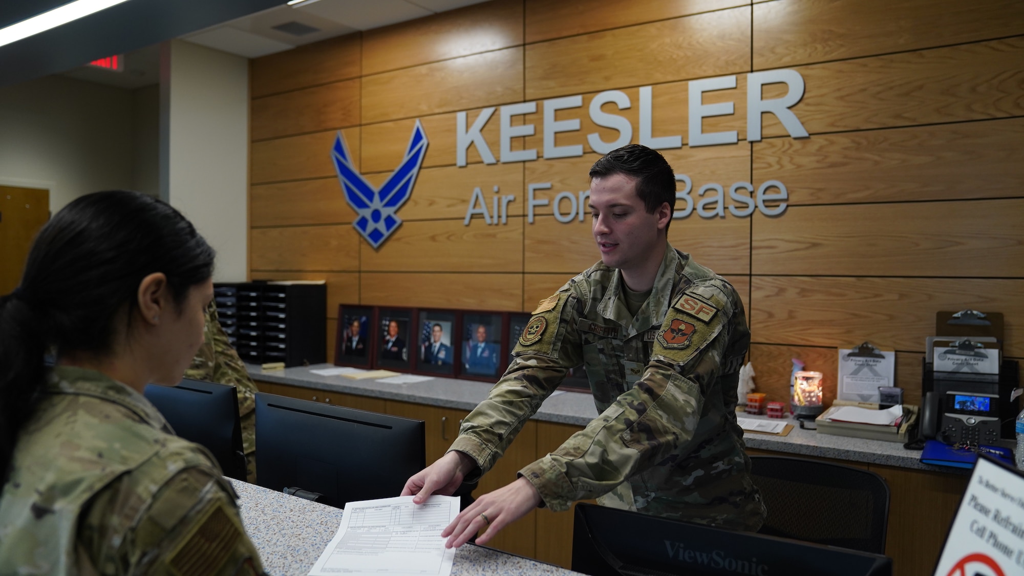 U.S. Air Force Senior Airman Daniel Griffith, 81st Security Forces Squadron defender, hands 2d Lt. Kristina Dean, 81st Training Wing public affairs officer, a form at the Division Street Gate Visitor’s Center on Keesler Air Force Base, Mississippi, March 9, 2023.