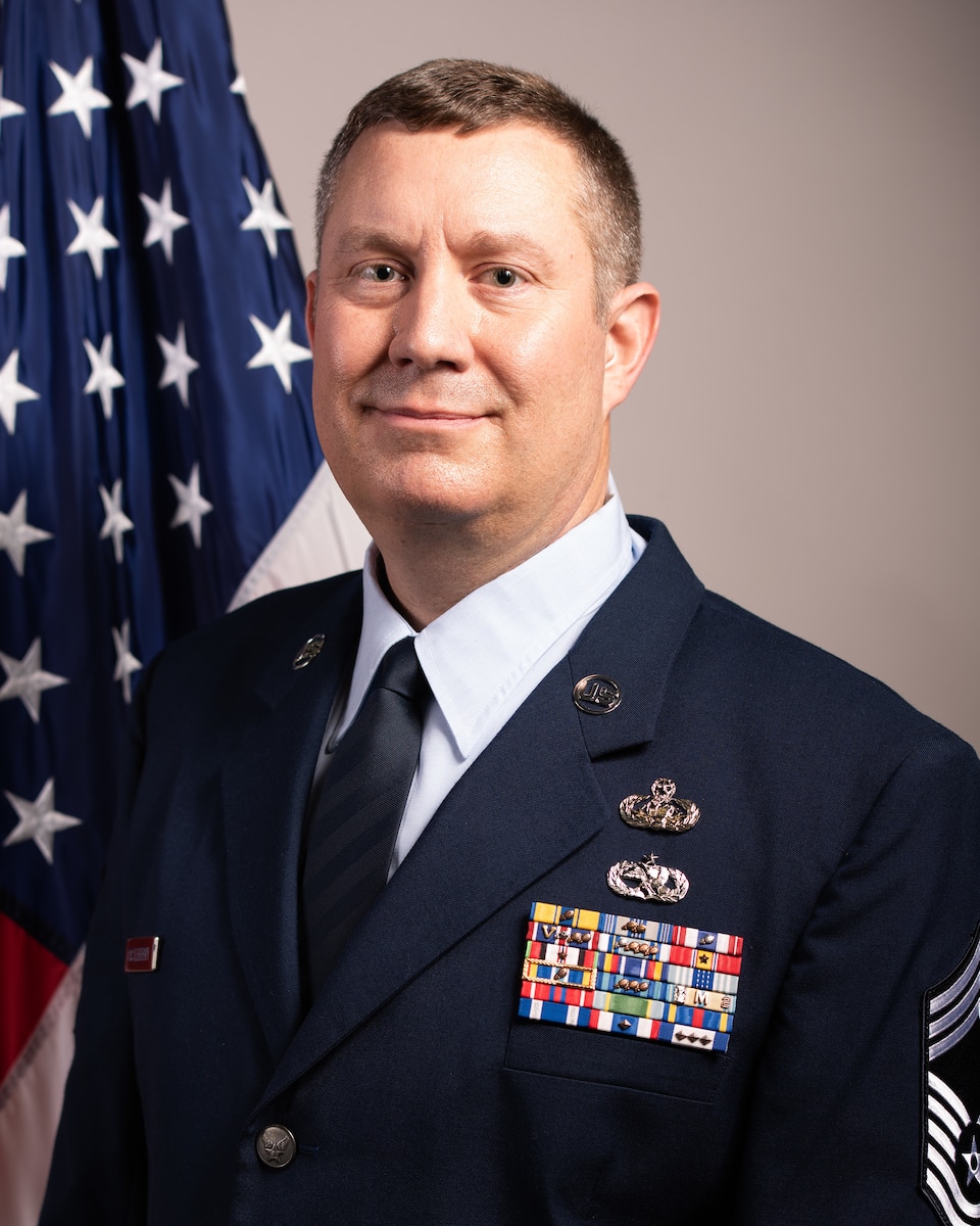 Stands in air Force dress uniform in front of American flag