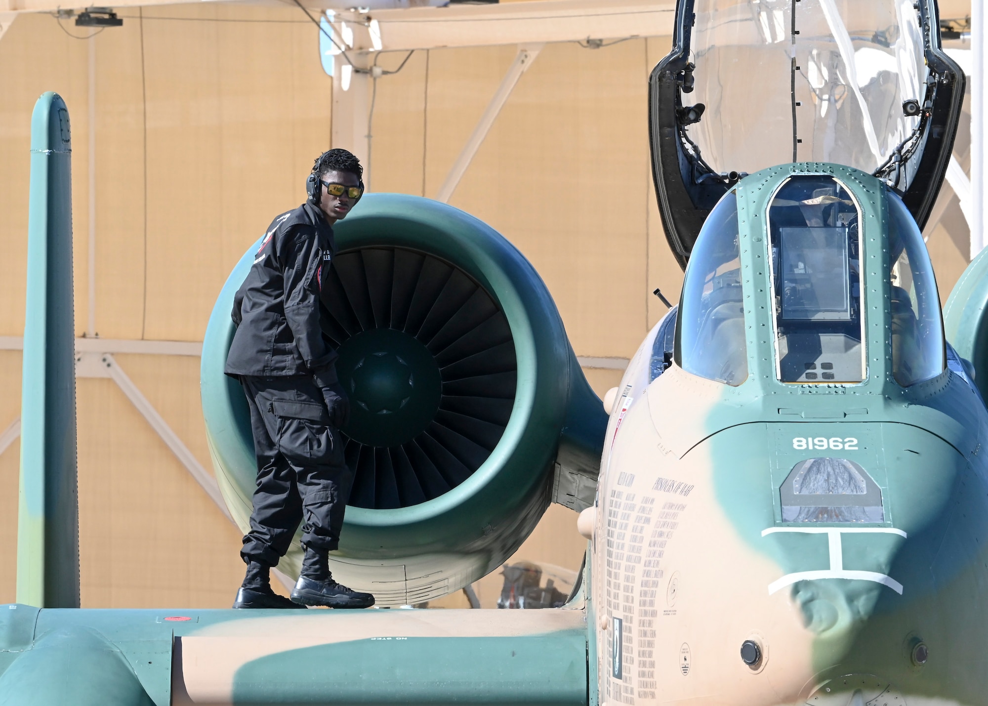 A photo of a man in a military uniform working on an aircraft.