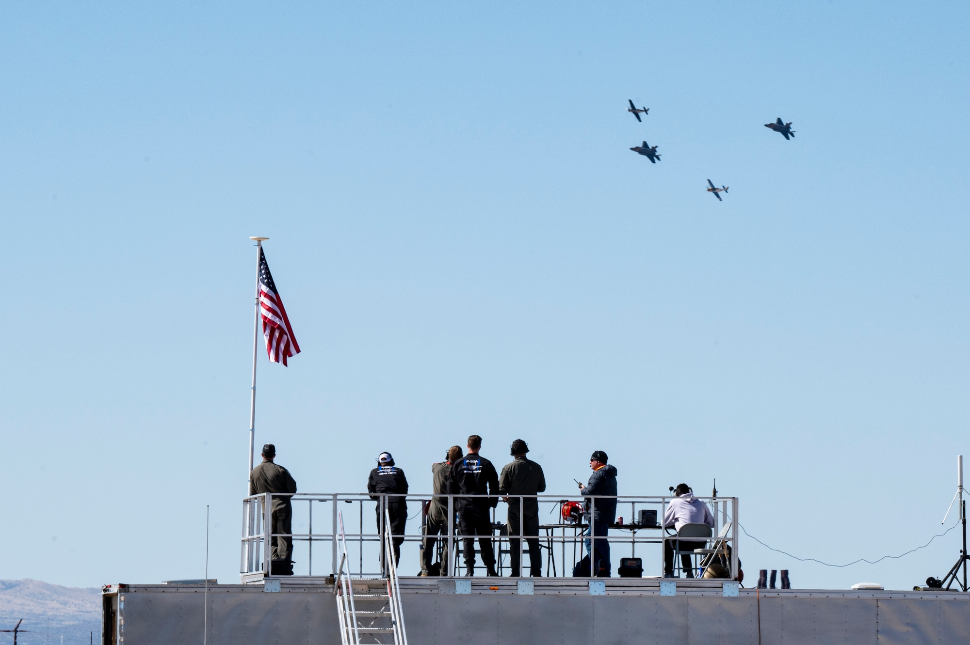 A photo of four aircraft flying in a formation while people watch.