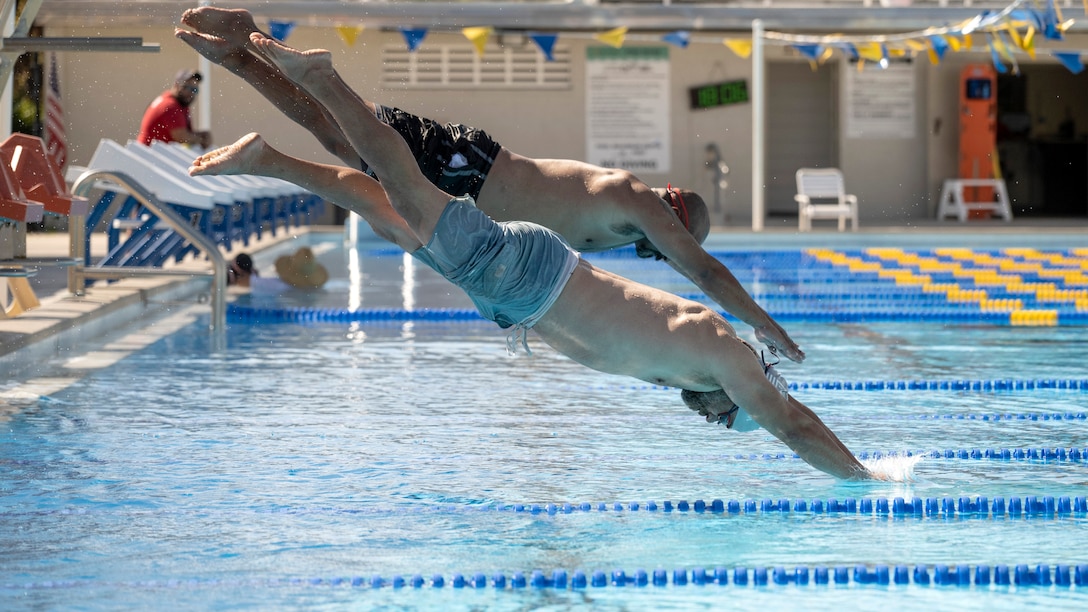 Swimmers dive into the pool from the blocks during practice.