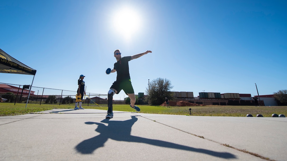 An athlete, silhouetted by the sun, whirls as he is about to throw a discus.