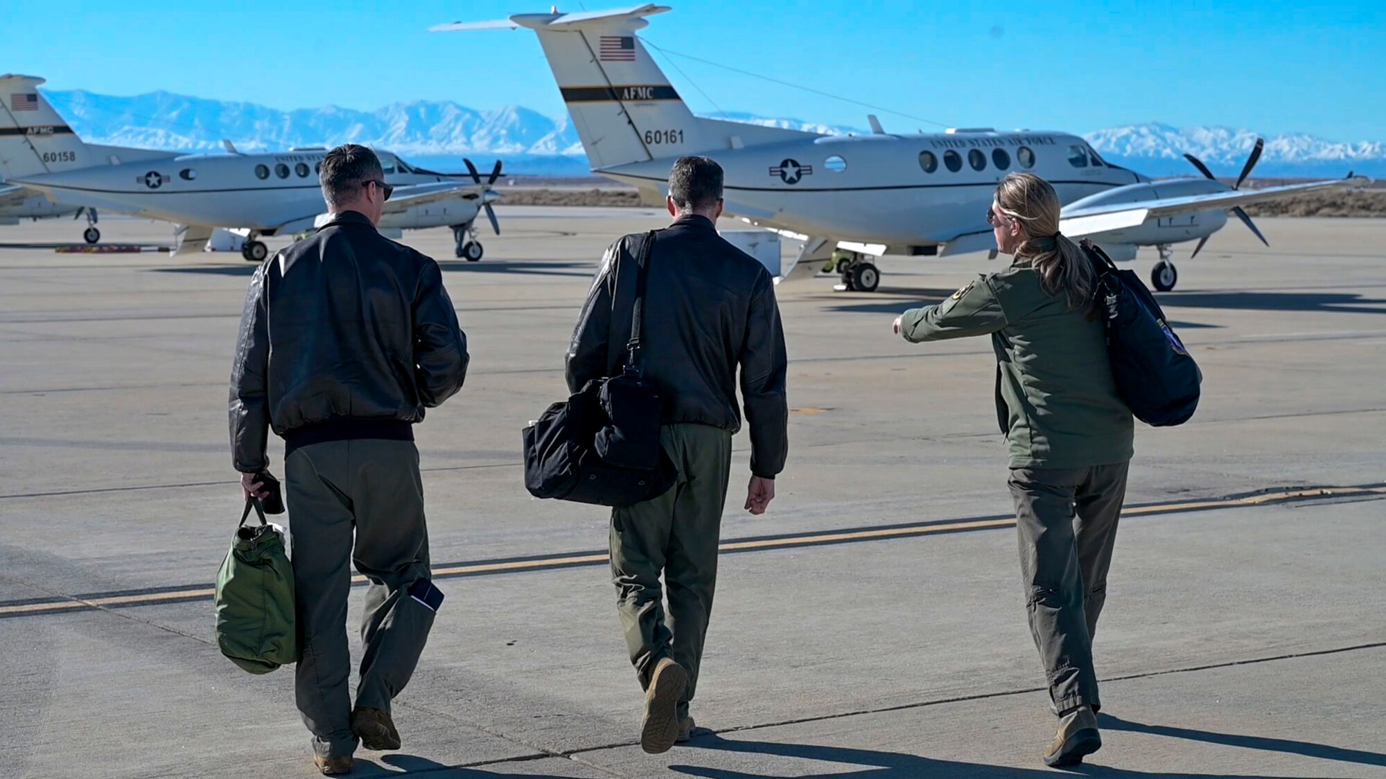 Col. Grant Mizell, Commander, 412th Operations Group, Lt. Col. Glenn Briscoe, Chief of C-12 Operations, 412th Operations Group and Jessica Peterson, Technical Director, 412th Operations Group step towards a C-12 Huron which will be used to conduct the Sidewinder low level flight survey through the Southern California wilderness.