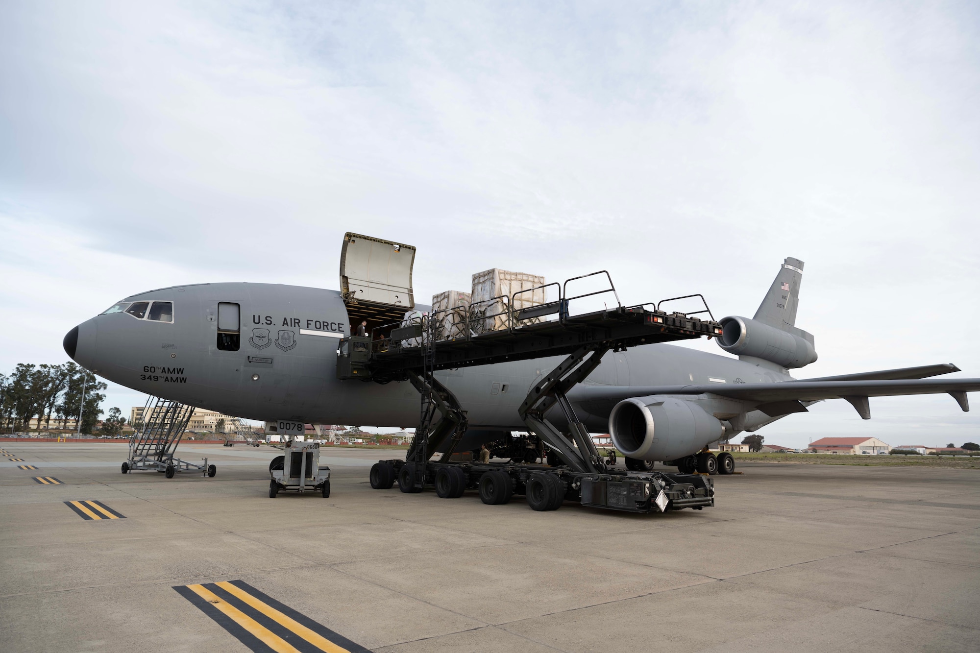 A large vehicle carrying cargo moves towards a big plane