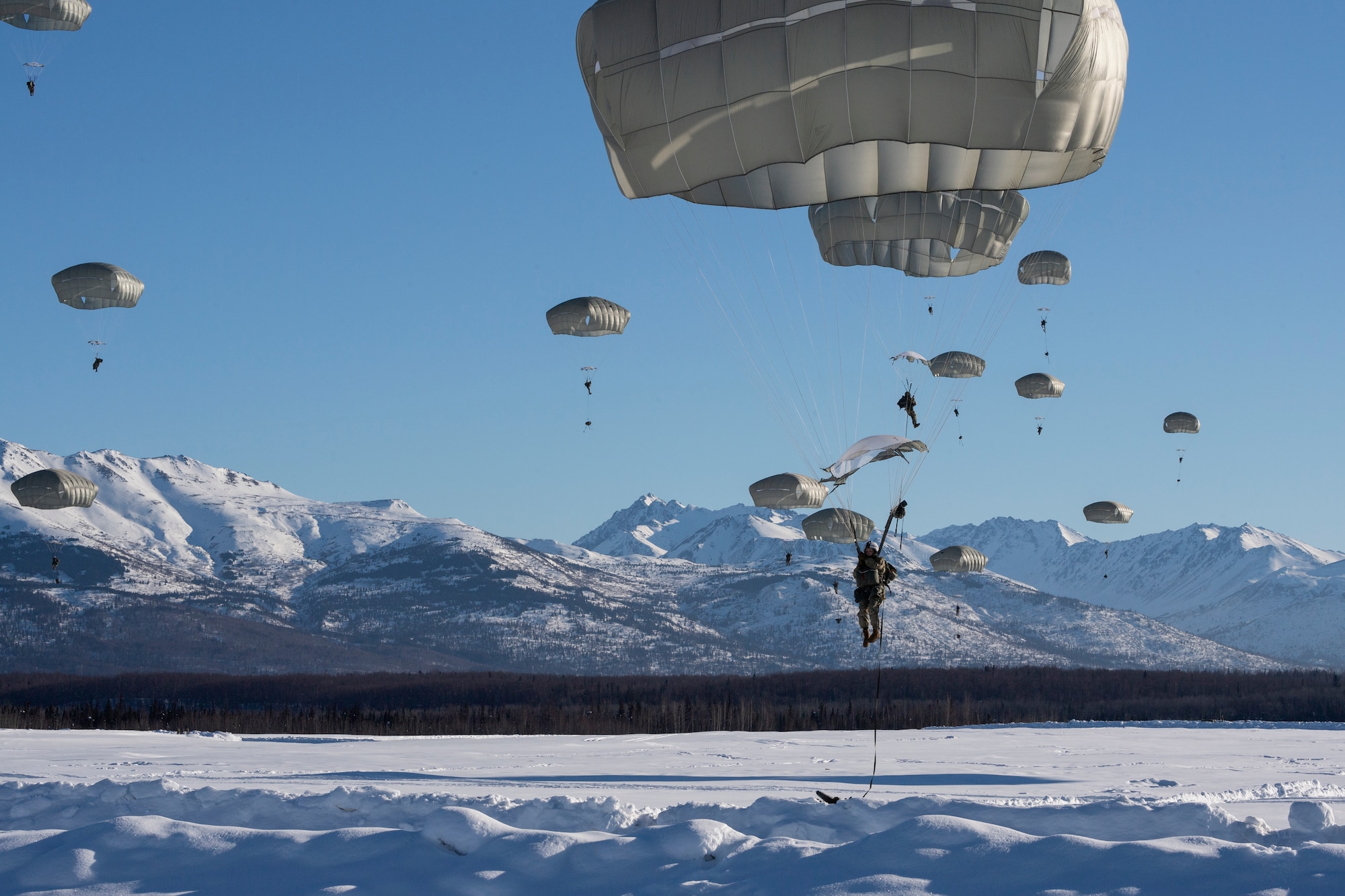 A photo of paratroopers descending upon a snowy drop zone