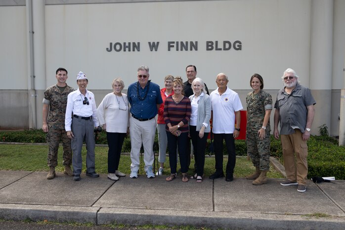 Jim Brueckner, great nephew of Medal of Honor recipient U.S. Navy Chief Petty Officer John W. Finn, poses for a photo with family, friends, and Marines in front of the John W. Finn Building during a visit to Marine Corps Base Hawaii, Feb. 27, 2023. The visit provided a visual and historic understanding of the attacks that occurred on Naval Air Station Kaneohe Bay on Dec. 7, 1941, in which Finn’s acts of heroism earned him the Congressional Medal of Honor. (U.S. Marine Corps photo by Cpl. Chandler Stacy)