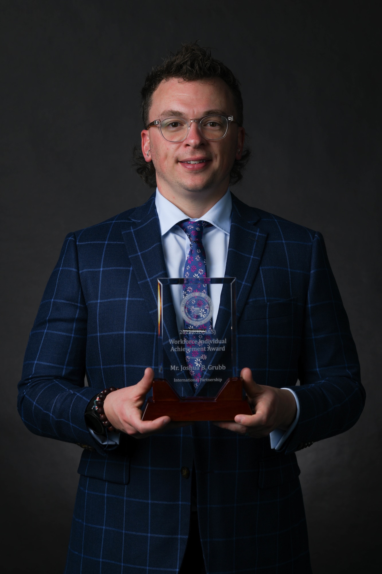 A contracting director stands with his award