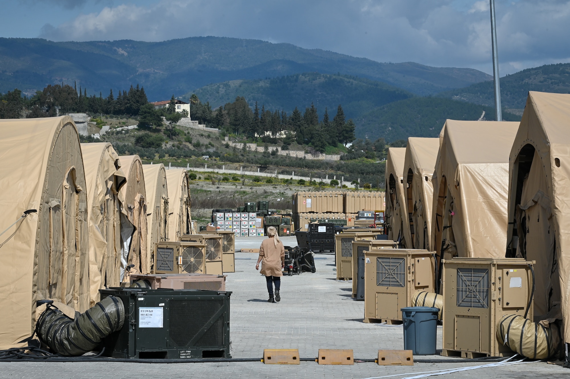 A field hospital worker walks down an alley of tents at the field hospital on the grounds of Mustafa Kemal University in Serinyol, Hatay, Türkiye, March 7, 2023.