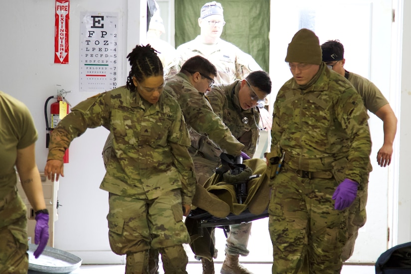 U.S. Soldiers carry a simulated casualty into a field hospital during an exercise at Fort Indiantown Gap, March 3, 2023. This exercise included responding to the scene of a mass casualty event, providing first aid and evacuating the simulated casualties to a field hospital where they received further care, all while being assessed by instructors with the Pennsylvania National Guard’s 4th Battalion, 166th Regiment Regional Training Institute (Medical Battalion Training Site). (U.S. Army National Guard photo by Maj. Travis Mueller)