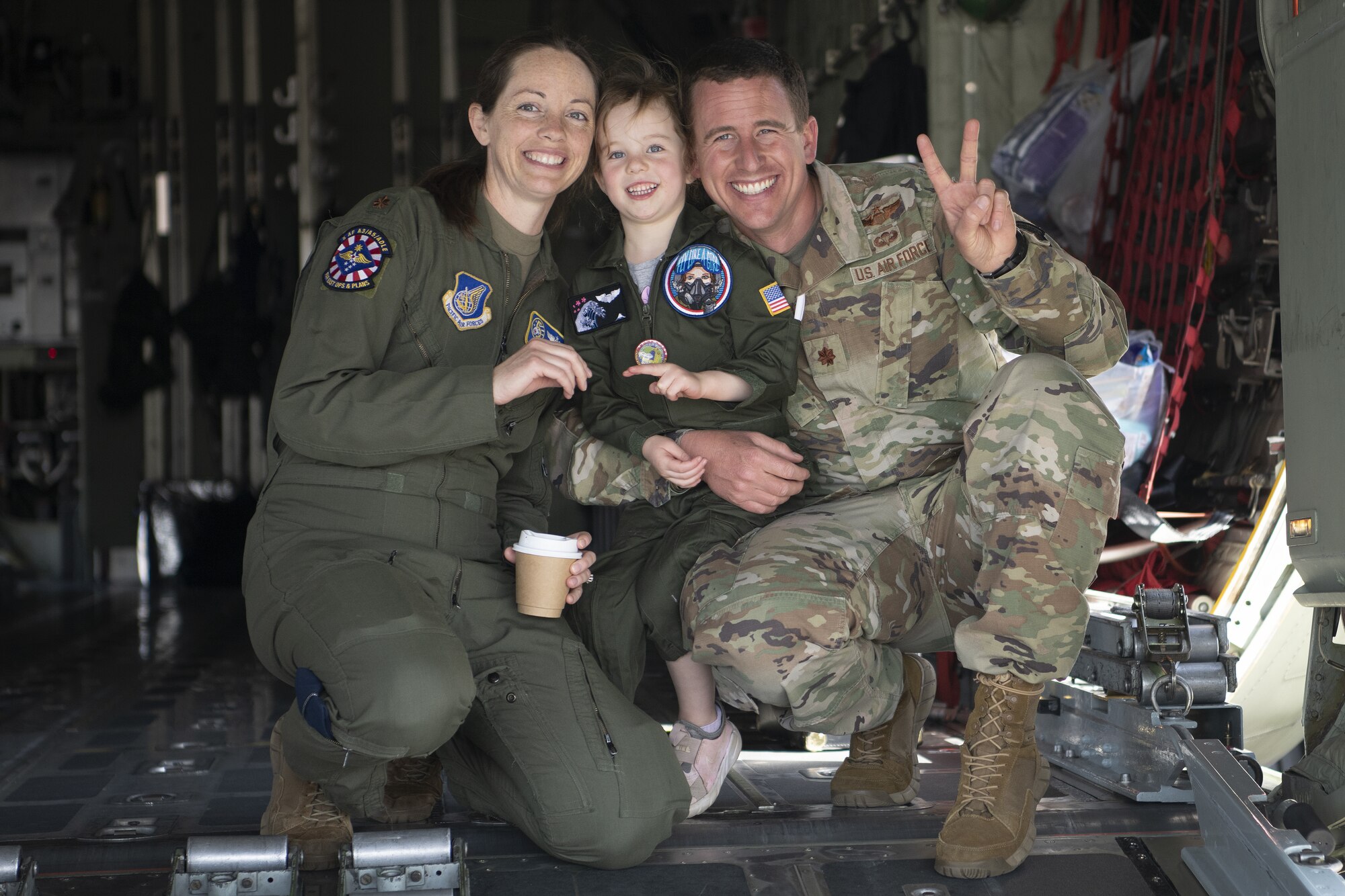 Maj. Keri Morris, left, and Maj. Andrew Morris, right,  pose for a photo with their daughter Audrey, 4-years-old, during a ‘Fly Girls’ aviation event.