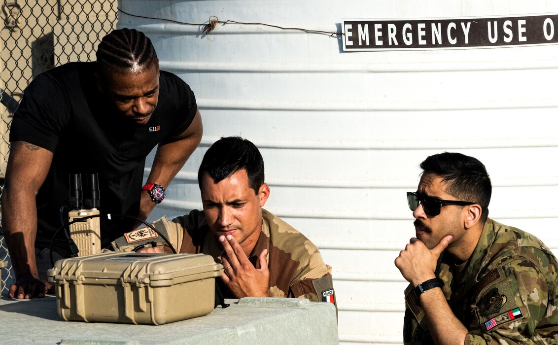 Dan Joseph (left), L-3 Harris contractor, French Army Master Sgt. Nicolas Eon (center), Battalion 5 CAV Regiment, Joint Terminal Attack Controller (JTAC), and U.S. Air Force Capt. Maheep Gill, 62nd Expeditionary Attack Squadron MQ-9 Reaper pilot, watch a live feed from a U.S. Air Force MQ-9 Reaper through a Tactical Network Reciever (TNR) at Al Dhafra Air Base, United Arab Emirates, March 7, 2023. Use of the TNR allows JTACs the ability to see what the unmanned aerial vehicle is seeing to help coordinate ground tactics in real time. (U.S. Air Force photo by Staff Sgt. Sabatino DiMascio)