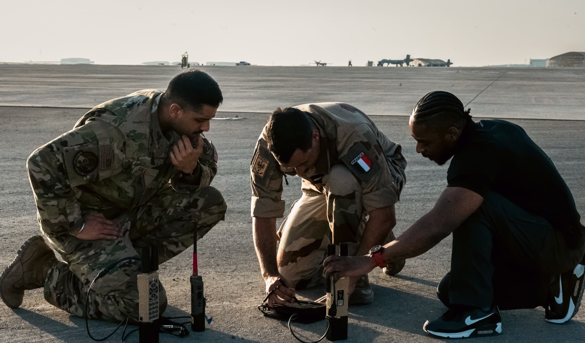 U.S. Air Force Capt. Maheep Gill (left), 62nd Expeditionary Attack Squadron MQ-9 Reaper pilot, French Army Master Sgt. Nicolas Eon (center), Battalion 5 CAV Regiment, Joint Terminal Attack Controller (JTAC) and Dan Joseph, L-3 Harris contractor, watch a live feed from a U.S. Air Force MQ-9 Reaper through a Tactical Network Receiver (TNR) at Al Dhafra Air Base, United Arab Emirates, March 7, 2023. The lessons and best practices learned here will be taken to other allied and partner nation militaries to increase interoperability. (U.S. Air Force photo by Staff Sgt. Sabatino DiMascio)