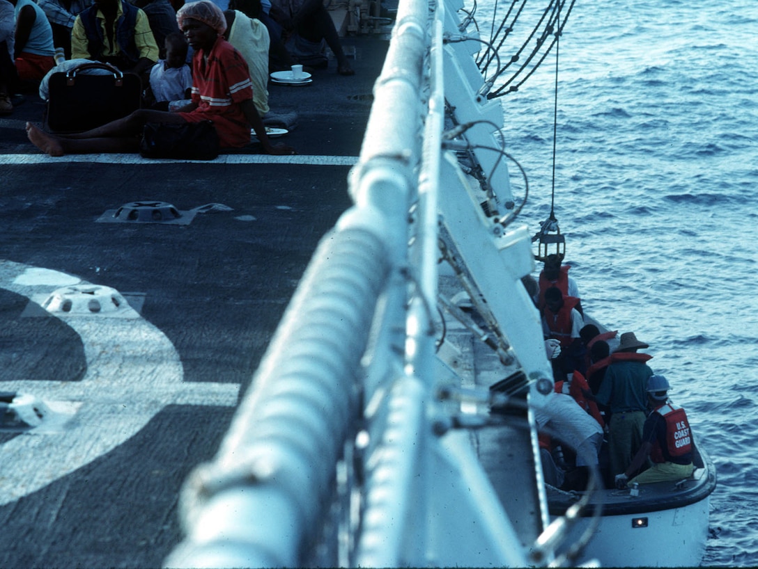 Haitian refugees sit on the flight deck of the USCGC Dauntless while more are brought aboard.