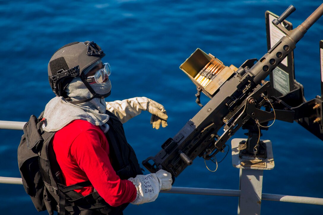 A sailor mans a weapon aboard a ship.