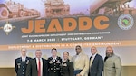 Seven DLA Europe & Africa Team members standing in front of Joint European Command and Africa Command conference sign.