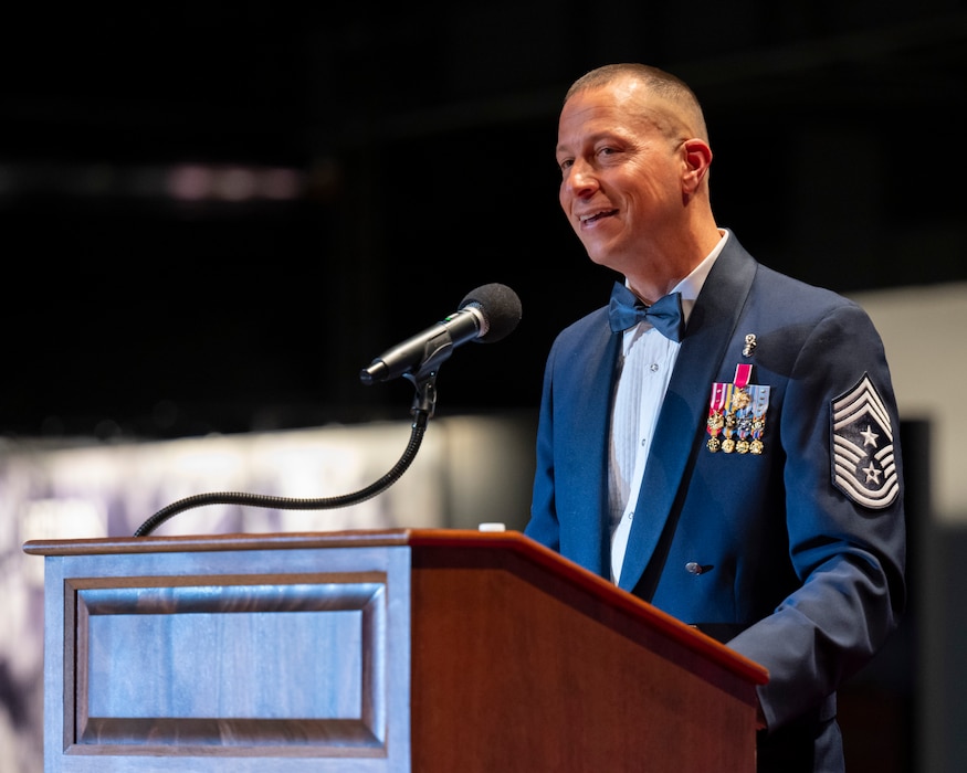 A smiling man in dress uniform speaks at a podium.