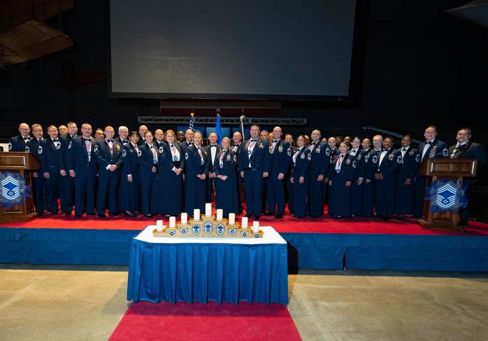 Approximately 40 men and women in mess dress uniform stand on a stage in the Air Force Museum.