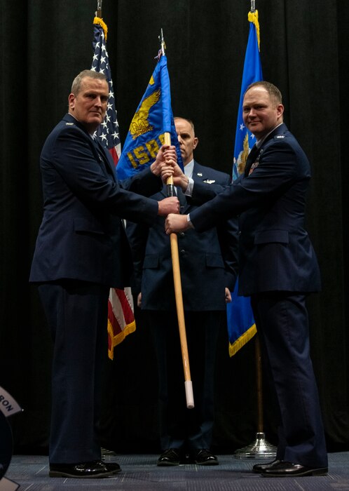 U.S. Air Force Col. Joe Marcinek, left, 655th Intelligence, Surveillance, and Reconnaissance Wing commander, Master Sgt. Scott Anderson, 655th ISR Group career assistance advisor, guidon bearer, and Col. Eric Bernkopf, 655 ISRG deputy commander, hold the guidon during the 665 ISRG change of command ceremony March 4, 2023, at the National Museum of the Air Force at Wright-Patterson Air Force Base, Ohio. Bernkopf assumed command from the outgoing commander, Col. Jennifer Mulder.