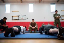 Sailors observe Junior Reserve Officers' Training Corps cadets’ pushups during the physical fitness assessment portion of a regional JROTC competition at Shelton High School in Shelton, Washington, Feb. 4, 2023. Active duty members from all service branches participated as judges for the competition, which brought local high school JROTC students together to compete in a series of four events including color guard, physical fitness, academics and a military-style ceremonial drill performance. (U.S. Navy photo by Mass Communication Specialist Seaman Sophia H. Brooks)