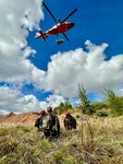 Guam Fire Department and U.S. Coast Guard members conduct rescue hoist training at Sella Bay Overlook in Guam on March 8, 2023. The exercise allowed the crews to assess the procedures each agency is familiar with and practice hoisting a rescue basket and a rescue swimmer from the aircraft. For the aircrew, it also served as an area familiarization to better understand the terrain and winds common on Guam's southwest coast.
