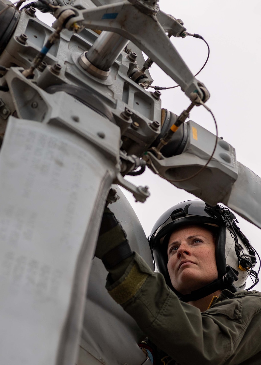 A woman looks at a helicopter propeller.