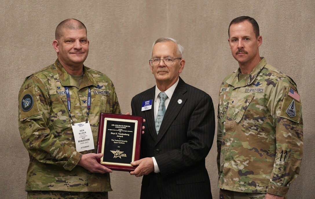 U.S. Space Force Col. Ken Klock, left, the National Security Space Institute commandant, and U.S. Space Force Brig. Gen. Todd Moore, right, Space Training and Readiness Command deputy commander, accept the 2022 Hoyt S. Vandenberg Award from Air & Space Force Association Chairman of the Board Bernie Skoch at the Air Warfare Symposium in Aurora, Colorado, March 8, 2023. The annual award, established in 1948, recognizes an individual or organization that has made significant contributions to aerospace education.