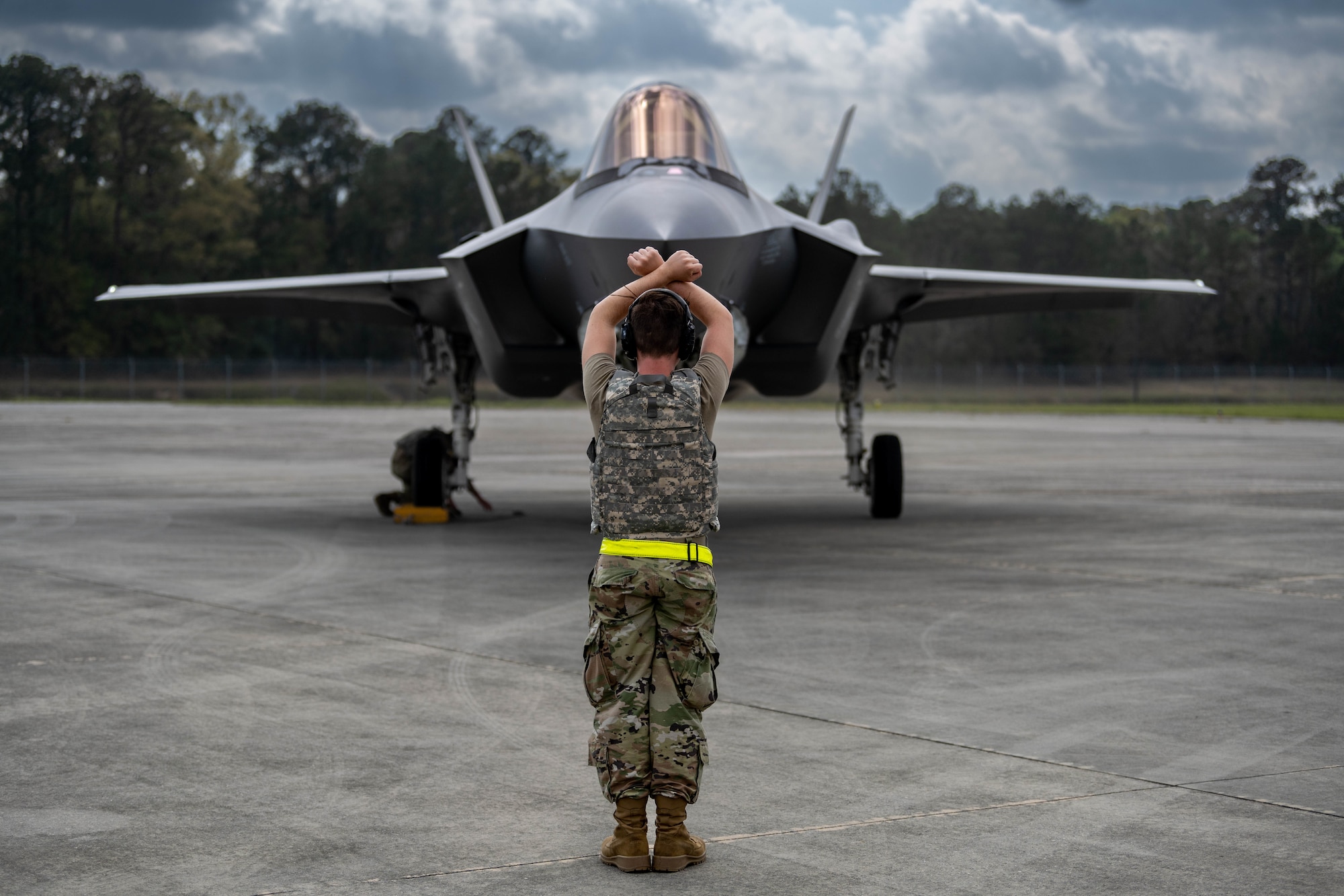 A photo of an F-35 maintainer marshalling a jet.