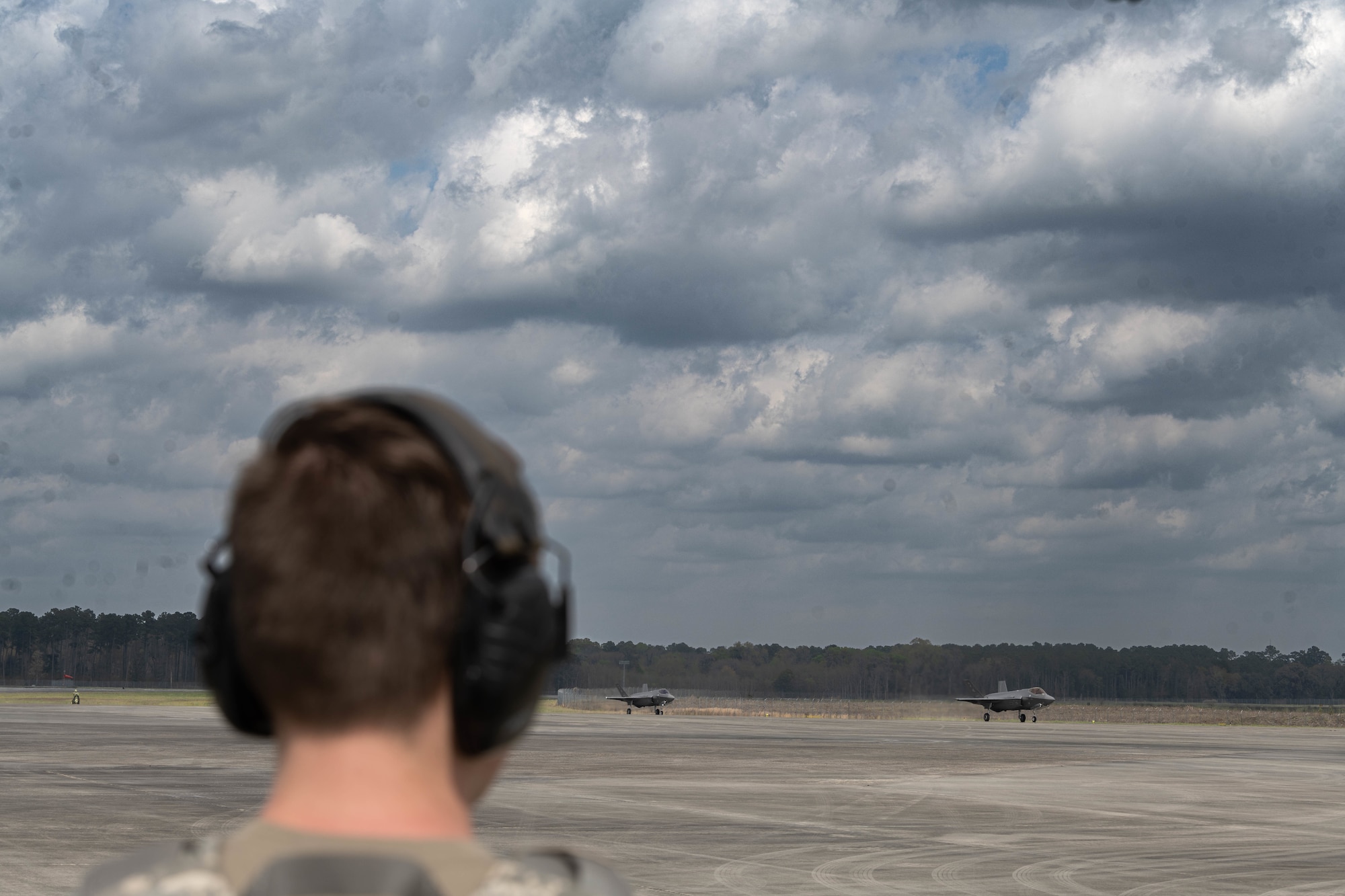 A photo of an F-35 maintainer watching jets taxi.