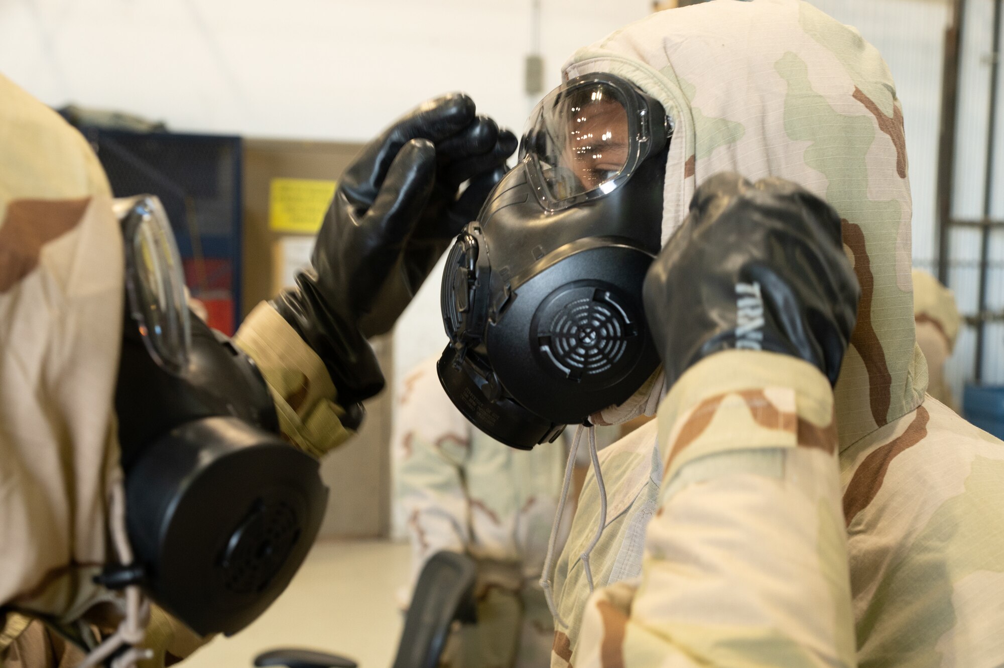 Airmen with the 436th Civil Engineer Squadron perform buddy checks after donning their mission oriented protective posture gear during a readiness exercise at Dover Air Force Base, Delaware, March 7, 2023. The exercise tested the abilities of the 436th Airlift Wing to generate, employ and sustain airpower across the world in a contested and degraded operational environment. (U.S. Air Force photo by Mauricio Campino)