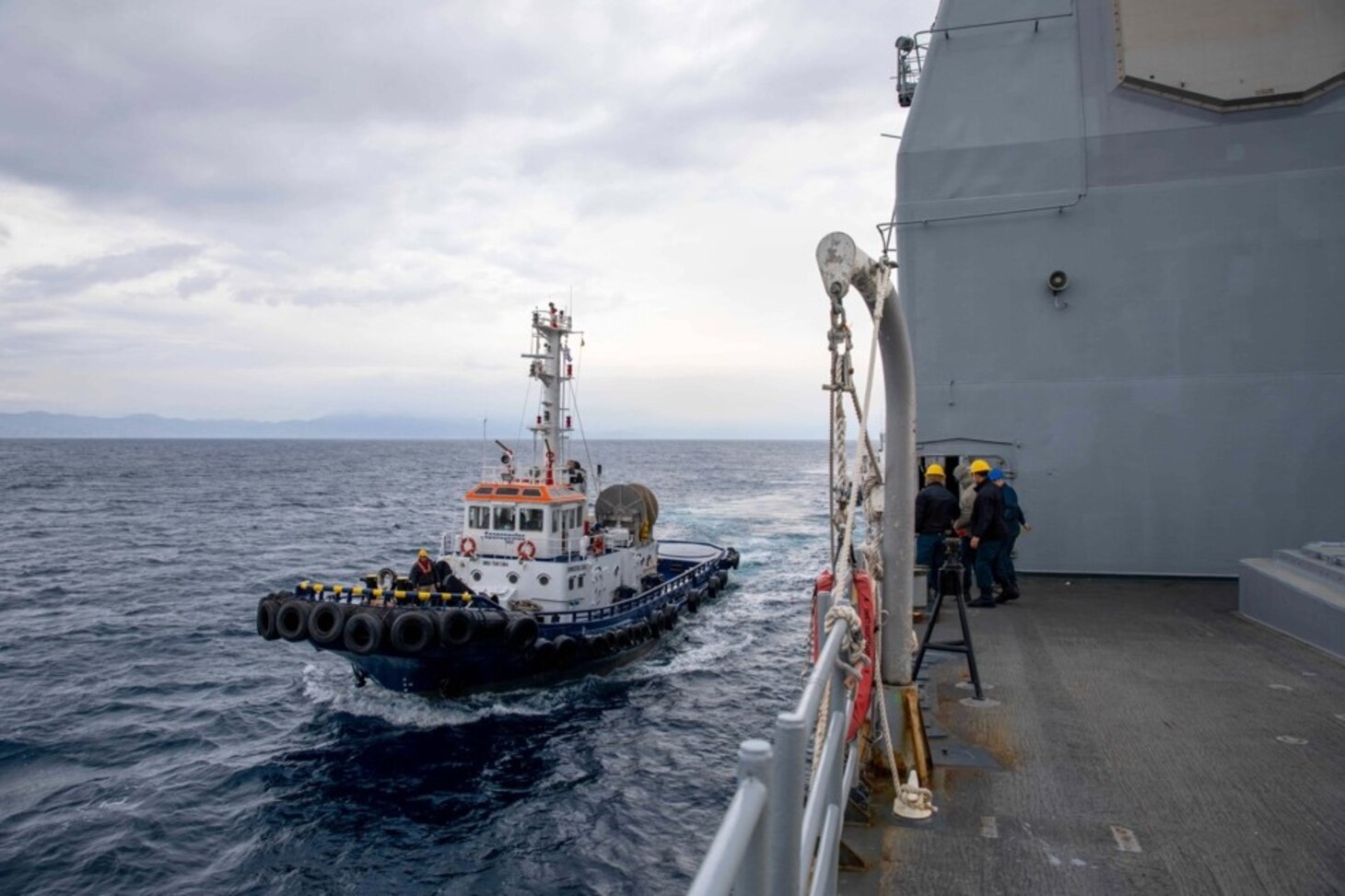 A tug boat prepares to pull the Ticonderoga-class guided-missile cruiser USS Leyte Gulf (CG 55) into port as the ship arrives in Rhodes, Greece for a scheduled port visit, March 11, 2023. The George H.W. Bush Carrier Strike Group is on a scheduled deployment in the U.S. Naval Forces Europe area of operations, employed by U.S. Sixth Fleet to defend U.S., allied, and partner interests.