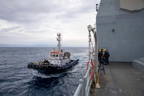 A tug boat prepares to pull the Ticonderoga-class guided-missile cruiser USS Leyte Gulf (CG 55) into port as the ship arrives in Rhodes, Greece for a scheduled port visit, March 11, 2023. The George H.W. Bush Carrier Strike Group is on a scheduled deployment in the U.S. Naval Forces Europe area of operations, employed by U.S. Sixth Fleet to defend U.S., allied, and partner interests.