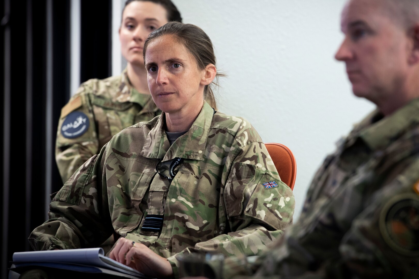 Woman in UK Space Command uniform listens to briefing