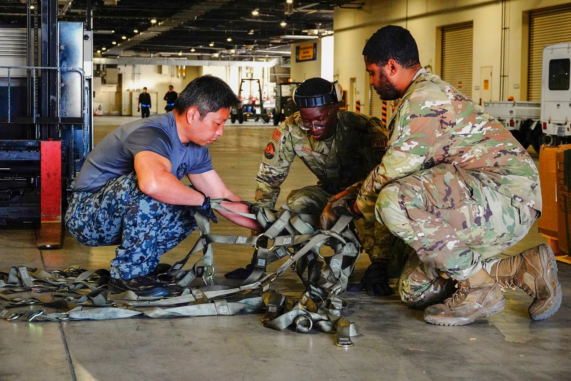 Three service members straightens cargo net