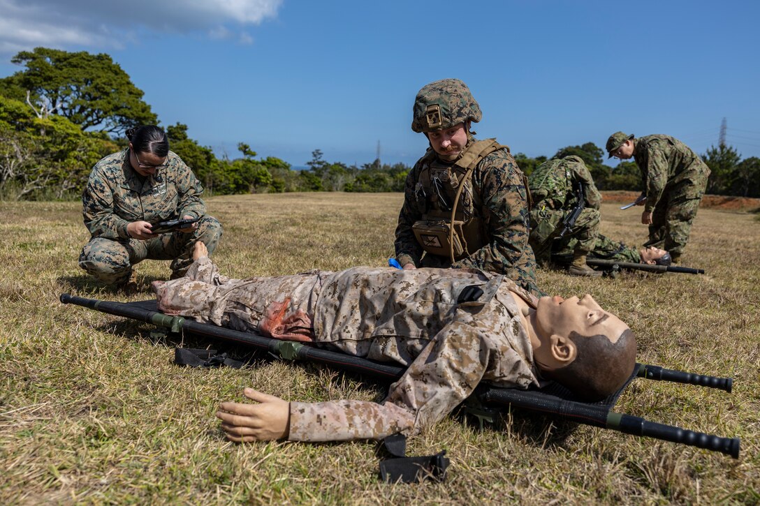 U.S. Navy corpsmen with the 31st Marine Expeditionary Unit, and soldiers with the 1st Amphibious Rapid Deployment Regiment, Japan Ground Self-Defense Force, asses the injuries of a simulated casualty during a bilateral casualty evacuation exercise on Camp Hansen, Okinawa, Japan, on March 10, 2023. The training enabled the bilateral medical team to practice in-route care and shock trauma field training during Iron Fist 23. Iron Fist is an annual bilateral exercise designed to increase interoperability and strengthen the relationships between the U.S. Marine Corps, the U.S. Navy, the JGSDF, and the Japan Maritime Self-Defense Force. (U.S. Marine Corps photo by Lance Cpl. Bridgette Rodriguez)