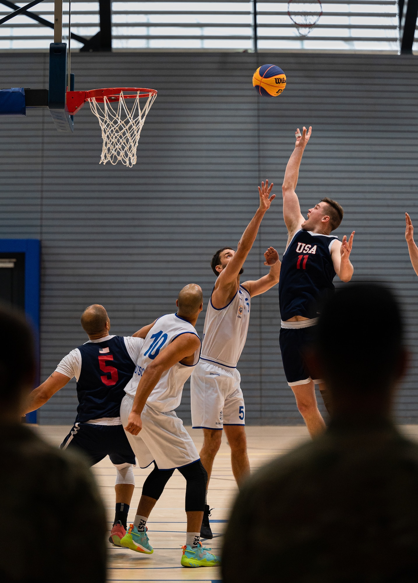 man jumps into the air with a ball focused on making it into a basket