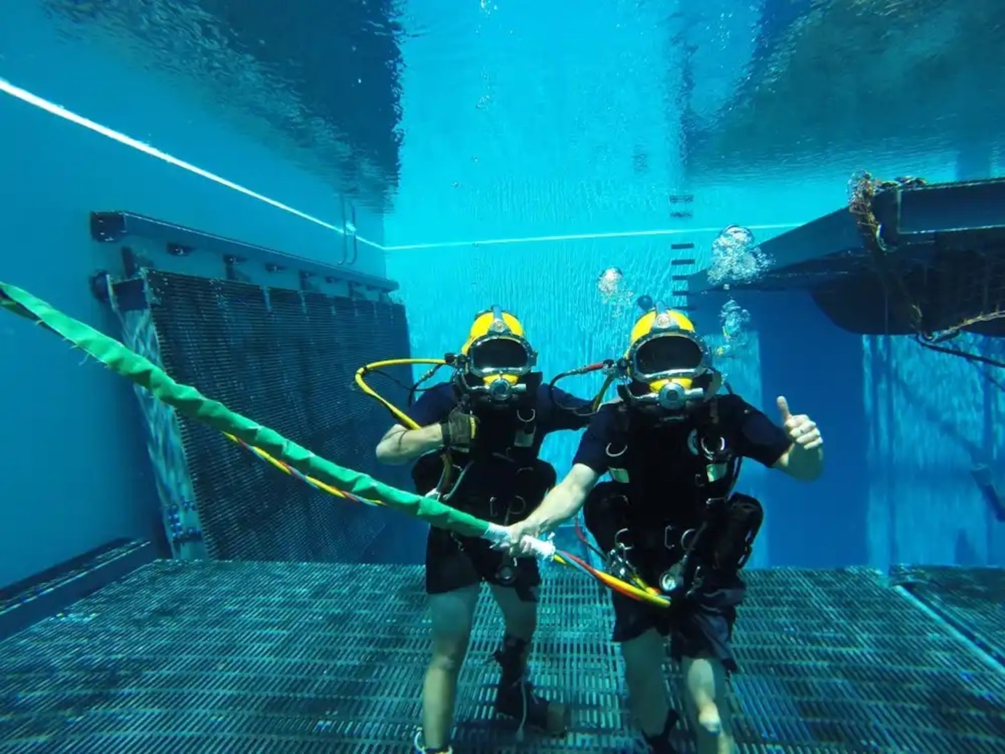Petty Officer 1st Class Chris Hall (left) diver, and Coast Guard Rear Adm. John Nadeau at the bottom of the pool demonstrating the capabilities of surface supplied diving gear at Naval Diving and Salvage Training Center in Panama City, Florida., July 9, 2015. Nadeau visited the NDSTC and performed a familiarization dive with Coast Guard Divers in the Aquatic Training Facility. (U.S. Coast Guard photo by Petty Officer 1st Class Michael Garst)