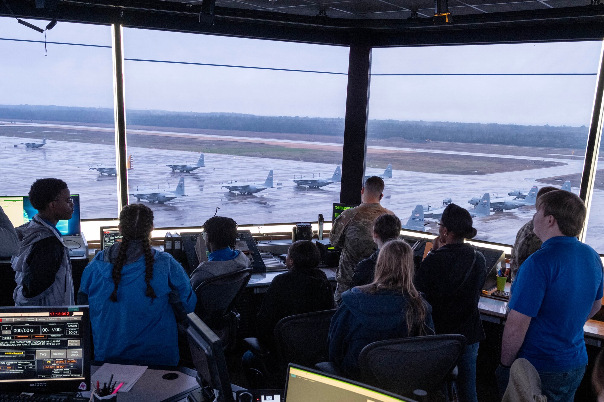 Students look out of an air traffic control tower at aircraft.