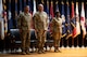 three people wearing u.s. army uniform stand in a group on a stage.