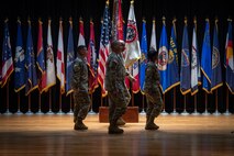 four people wearing u.s. army uniform stand in a group on a stage.