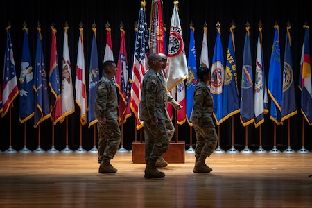 four people wearing u.s. army uniform stand in a group on a stage.