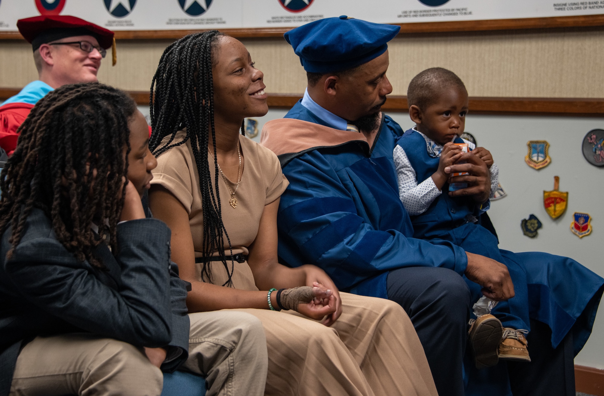 The family of Senior Master Sgt. Anique S. McElveen looks on as she receives her doctorial hood during a ceremony at the Enlisted Heritage Hall on Maxwell Air Force Base, Gunter Annex, March 10, 2023.  She is part of just .007 percent of enlisted Airmen to receive a doctoral degree. McElveen is the superintendent of the College of Academic Management at the Community College of the Air Force. (U.S. Air Force photo/Brian Ferguson)
