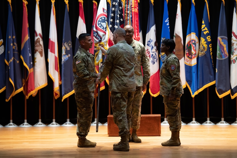 four people wearing u.s. army uniform stand in a group on a stage.