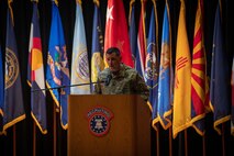 man wearing u.s. army uniform stands behind a podium.