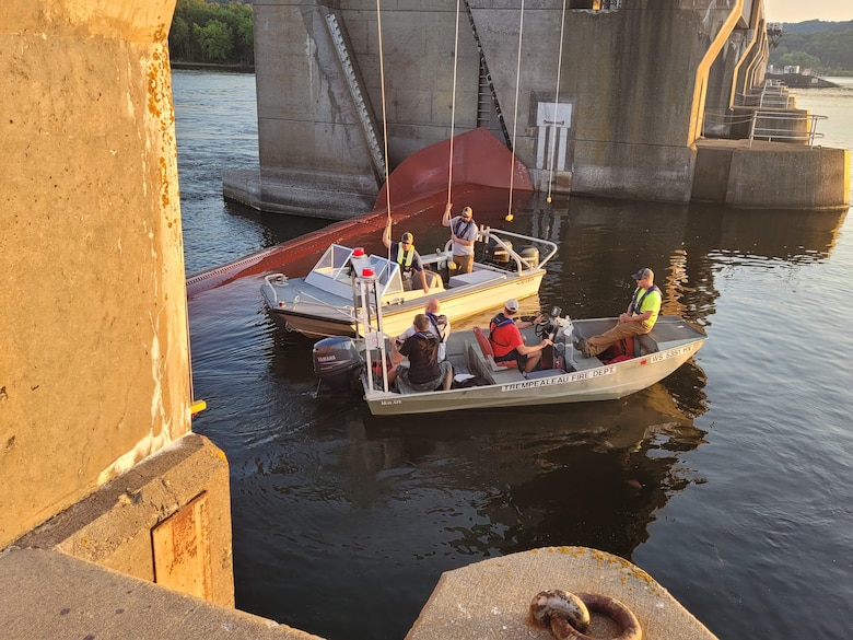 A group of people in two boats near a concrete structure on the water.