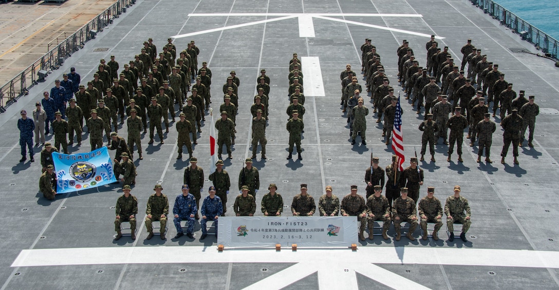 OKINAWA, JAPAN (Mar. 12, 2023) Marines assigned to the 31st Marine Expeditionary Unit, Sailors assigned the forward deployed amphibious assault carrier USS America (LHA 6), and members of the Japan Maritime Self-Defense Force and Japan Ground Self-Defense Force pose for a photo during the closing ceremony for Exercise Iron Fist aboard the Japan Maritime Self-Defense Force landing ship tank JS Osumi (LST-4001) while moored in Okinawa, Japan, Mar. 12. Iron Fist is an annual bilateral exercise designed to increase interoperability and strength the relationships between the U.S. Marine Corps, the U.S. Navy, the Japan Ground Self-Defense Force, and the Japan Maritime Self-Defense Force. America, lead ship of the America Amphibious Ready Group, is operating in the 7th Fleet area of operations. 7th Fleet is the U.S. Navy’s largest forward-deployed numbered fleet, and routinely interacts and operates with Allies and partners in preserving a free and open Indo-Pacific region. (U.S. Navy photo by Mass Communication Specialist 1st Class Shelby M. Tucker)